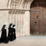 Un grupo de religiosas, protegidas con mascarillas, ante una las puertas de la Catedral de Valencia