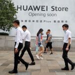 Ciudadanos chinos caminan ante un anuncio de Huawei en Pekín