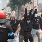 Agentes de la Ertzaintza tratan de contener a un grupo de personas que intentan boicotear un mitin de Vox lanzando piedras y botes de humo