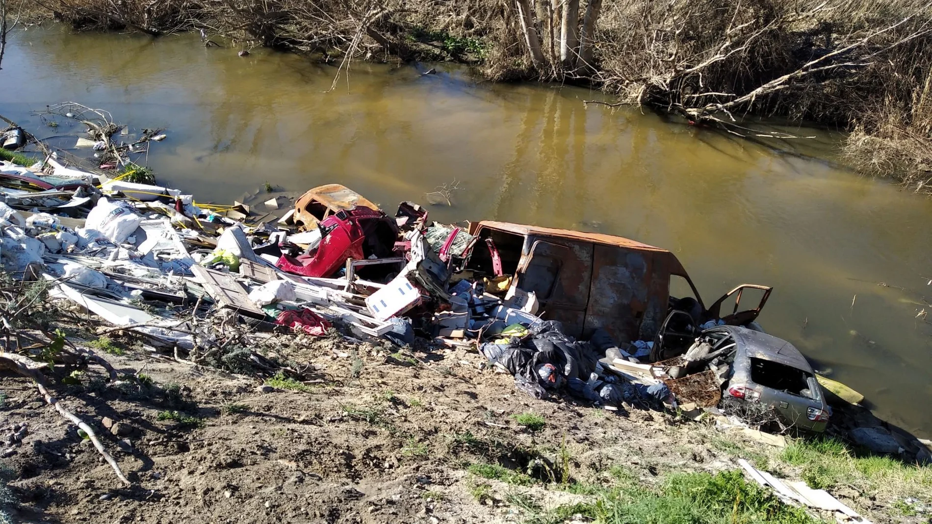Escombros , basuras, electrodomésticos y hasta coches calcinados forman los vertidos ilegales sobre el río Guadarrama