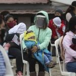Women hold their children as they wait to vaccinate them during a vaccination campaign in the Villa El Salvador neighborhood of Lima, Peru, Friday, June 26, 2020. In an attempt to strengthen primary health care for vulnerable populations in the country, the Ministry of Health has increased services. (AP Photo/Martin Mejia)