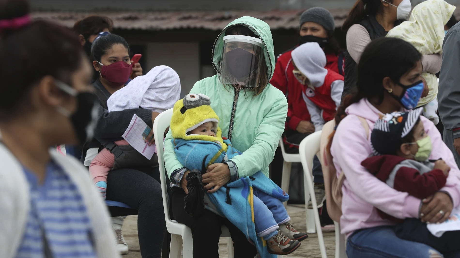 Women hold their children as they wait to vaccinate them during a vaccination campaign in the Villa El Salvador neighborhood of Lima, Peru, Friday, June 26, 2020. In an attempt to strengthen primary health care for vulnerable populations in the country, the Ministry of Health has increased services. (AP Photo/Martin Mejia)
