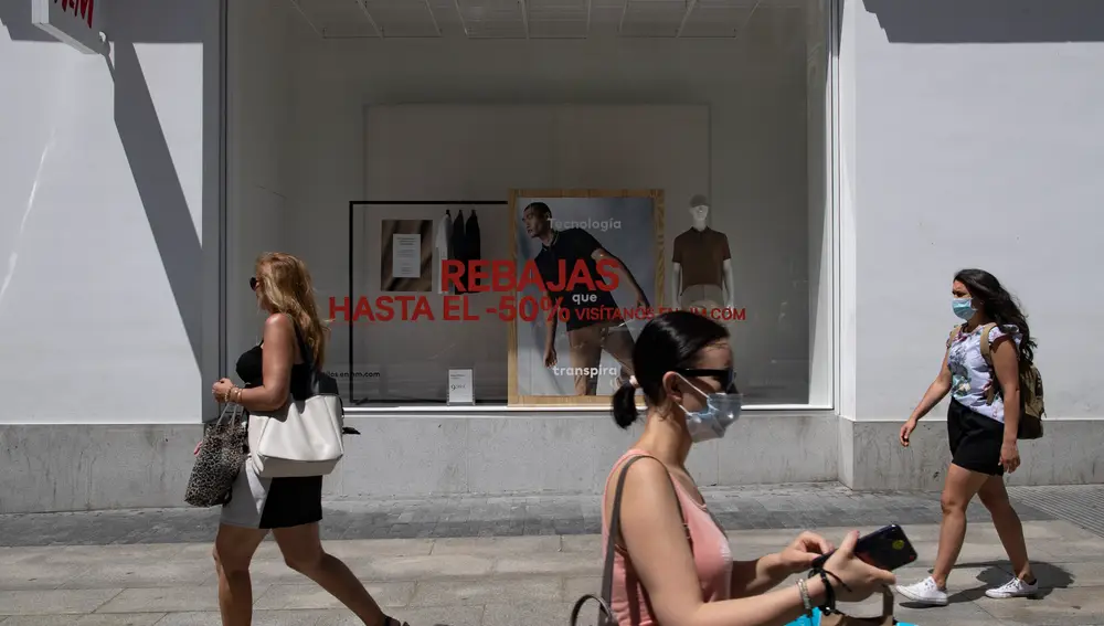 Varias personas pasean al lado de una tienda de la capital con carteles de descuentos, durante el segundo día de rebajas, en Madrid (España), a 26 de junio de 2020.26 JUNIO 2020;REBAJAS;HYM;MADRID;COMPRAEduardo Parra / Europa Press26/06/2020