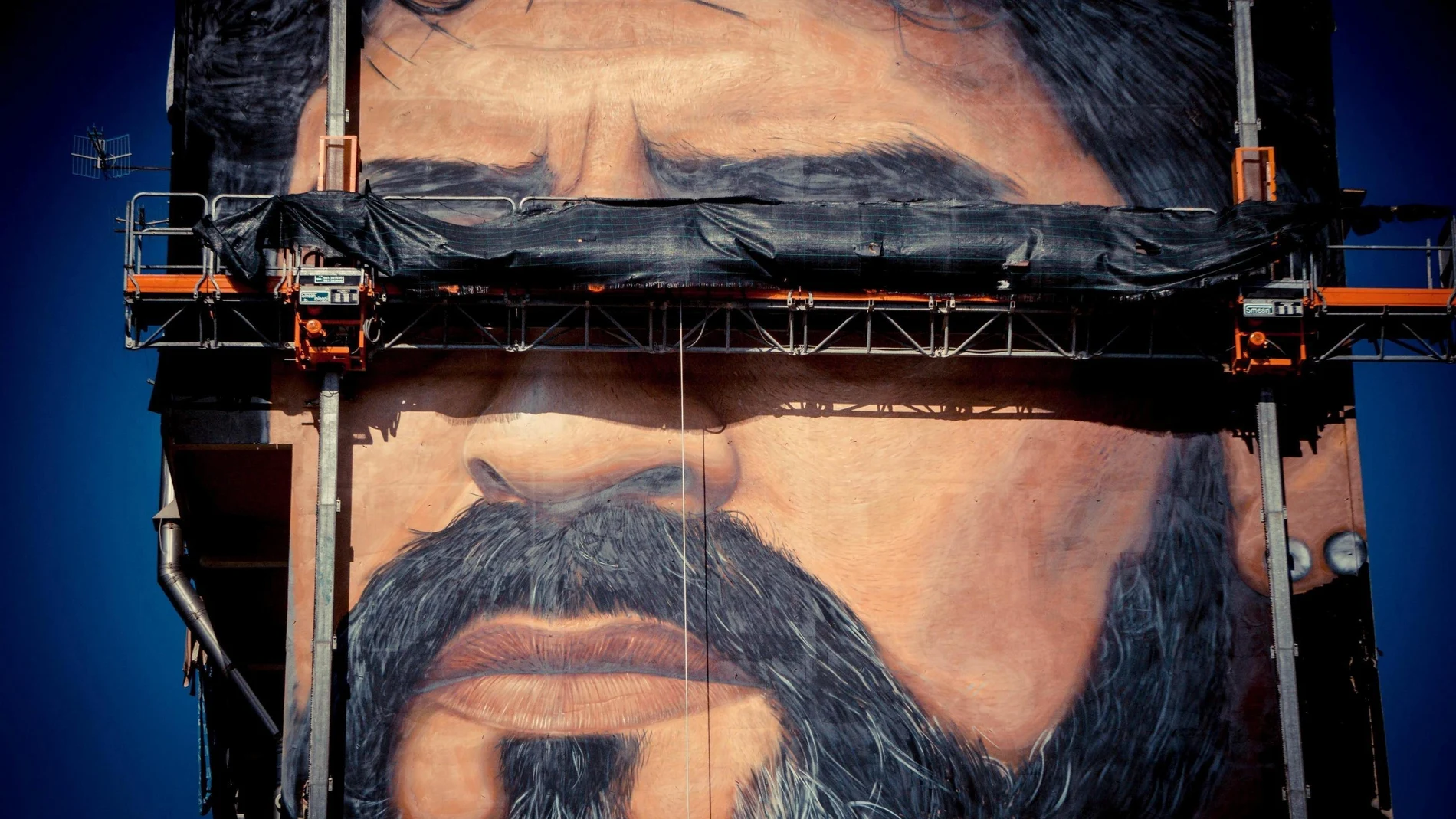 Vista de un mural del artista italiano Jorit Agoch, en el que aparece retratado el exfutbolista argentino Diego Armando Maradona, en un edificio de Nápoles
