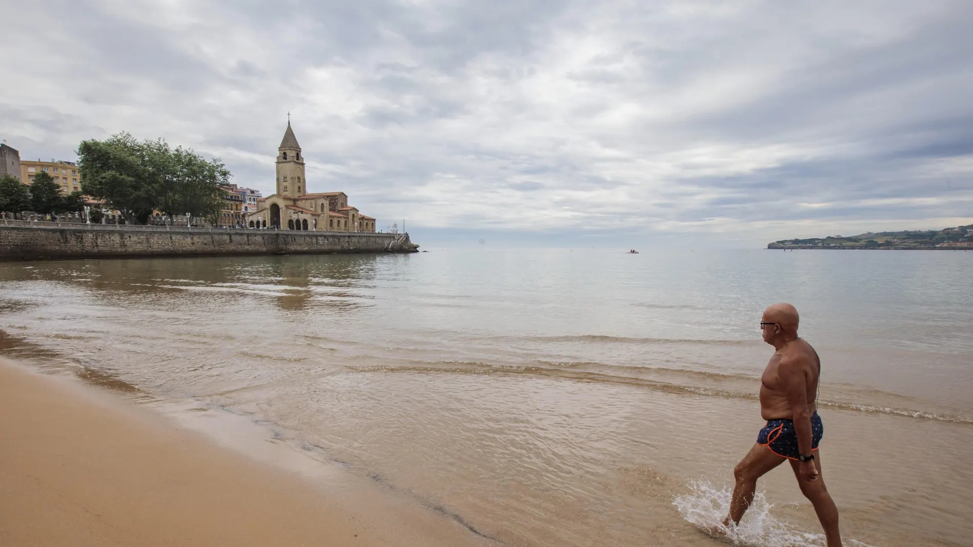 Un hombre sale de la playa de San Lorenzo de Gijón