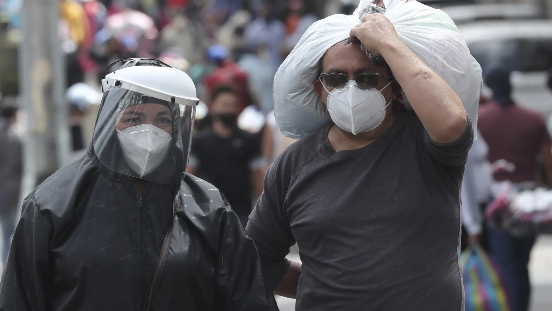 People wearing masks and face shields walk in the capital's downtown amid the new coronavirus pandemic in Quito, Ecuador, Monday, June 29, 2020. (AP Photo/Dolores Ochoa)