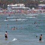 Un gran número de personas se refresca en las aguas de la playa de la Malvarrosa el primer día de julio