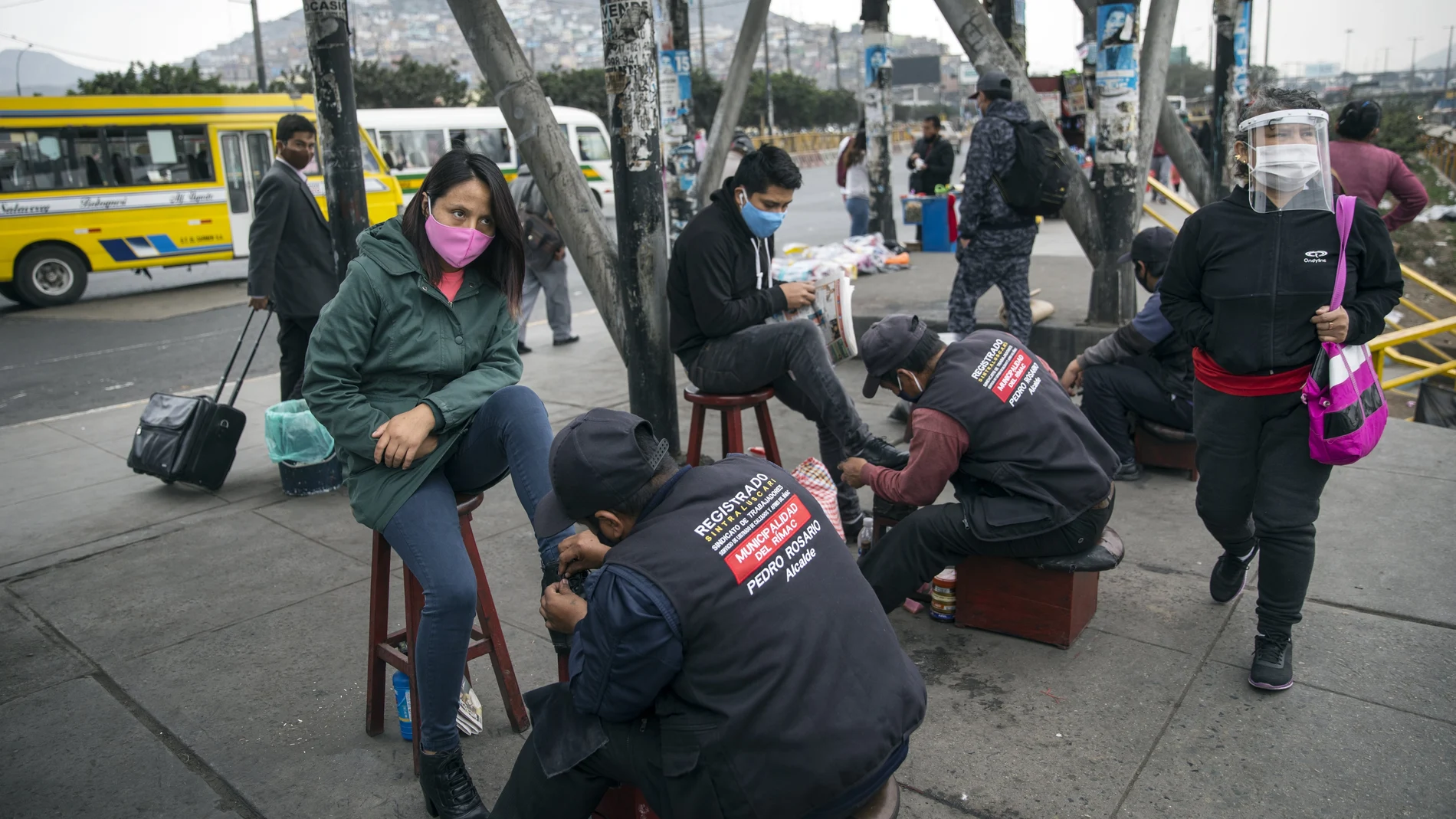 Wearing a mask to curb the spread of the new coronavirus, Daisy Avila Paredes, left, has her boots shined in Lima, Peru, Wednesday, July 1, 2020. (AP Photo/Rodrigo Abd)