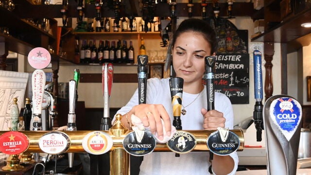 Una empleada de un pub londinenses limpia antes de la esperada reapertura de este sábado