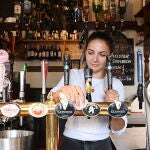 Una empleada de un pub londinenses limpia antes de la esperada reapertura de este sábado