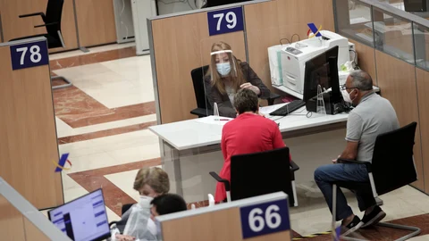 Una trabajadora de la Oficina de la Agencia Tributaria en la Calle Guzmán el Bueno (Madrid) atiende a dos personas para confeccionar la declaración de la Renta de 2019