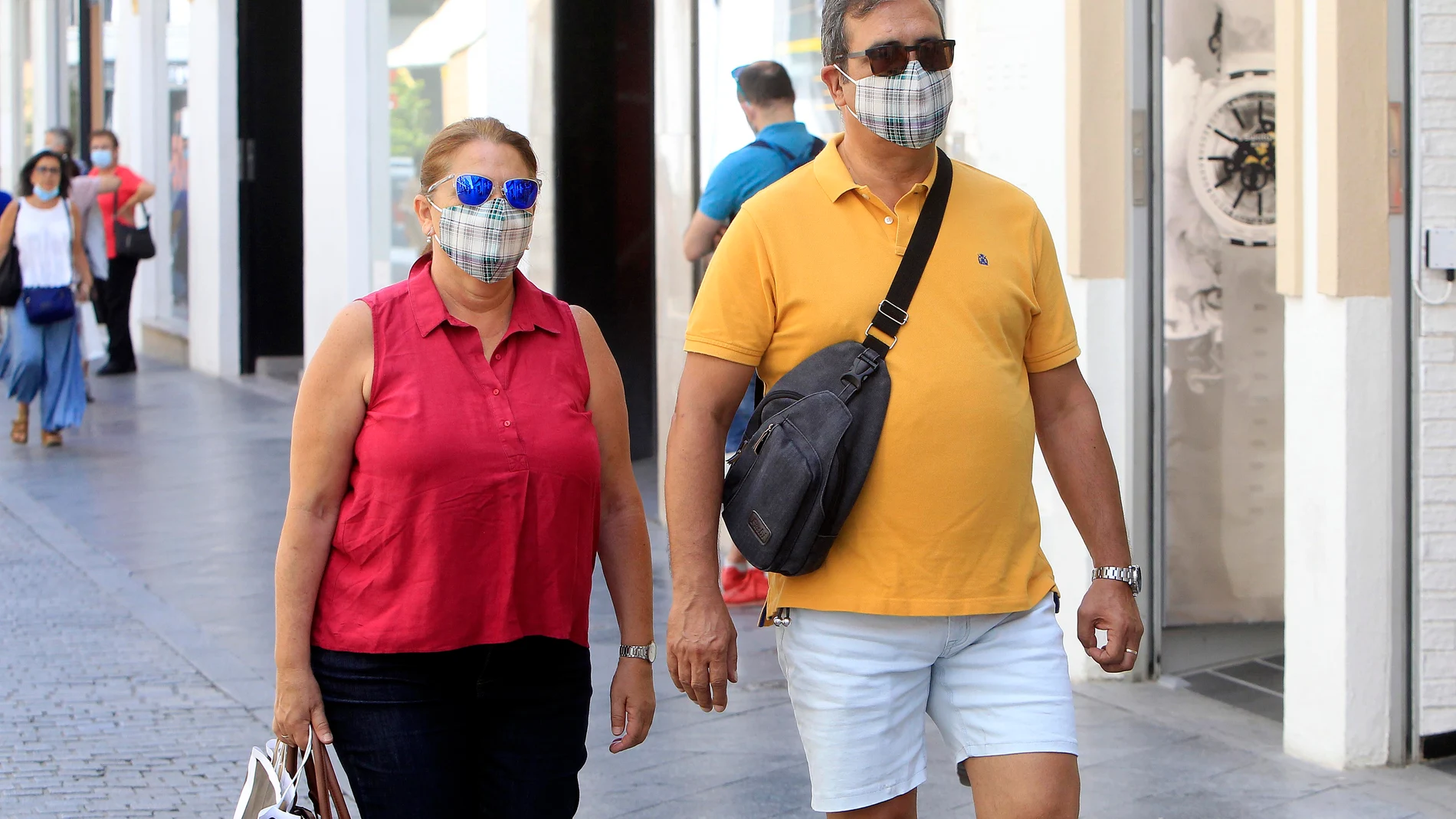 Transeúntes pasean por Sevilla, equipados con mascarillas, en una jornada de julio poco habitual