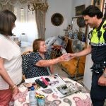Un agente de la Policía Local de los Tomares atiende a una mujer mayor en su domicilio