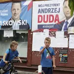 Dos niños polacos pasean junto a los carteles electorales del actual presidente, Andrzej Duda, y el candidato liberal, Rafal Trzaskowski, en Raciaz