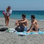 Una vigilante de playa informa a dos jóvenes de las nuevas medidas que acaban de entrar en vigor sobre el uso obligatorio de la mascarilla en todos los espacios abiertos y cerrados bajo multas de 100 euros