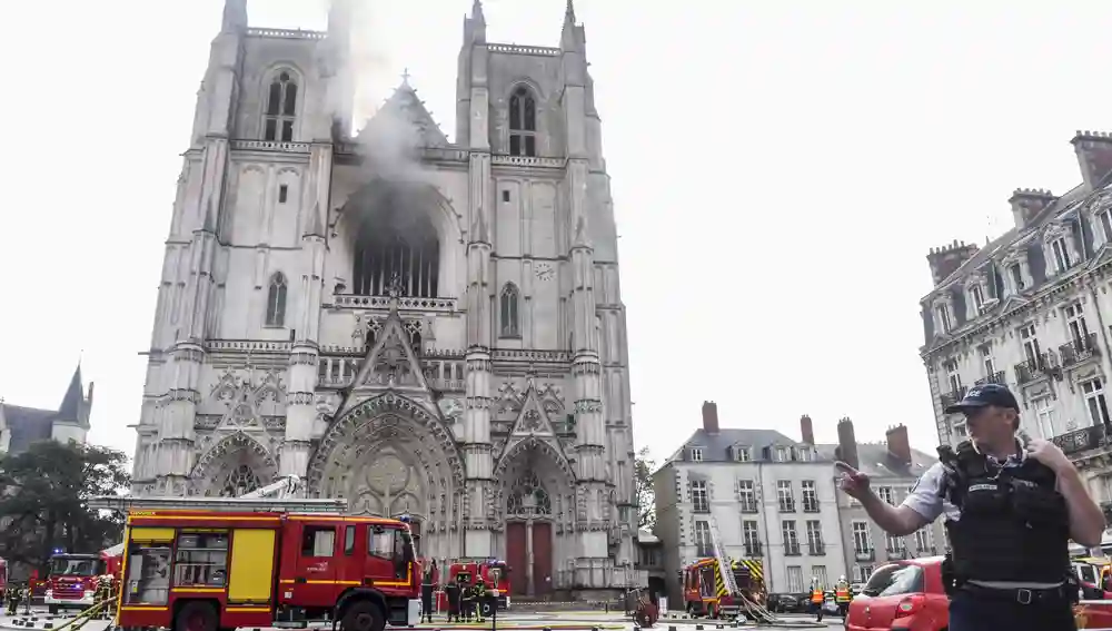 Un policía controla el paso a la plaza de la catedral, mientras los bomberos comprueban que se han extinguido definitivamente las llamas
