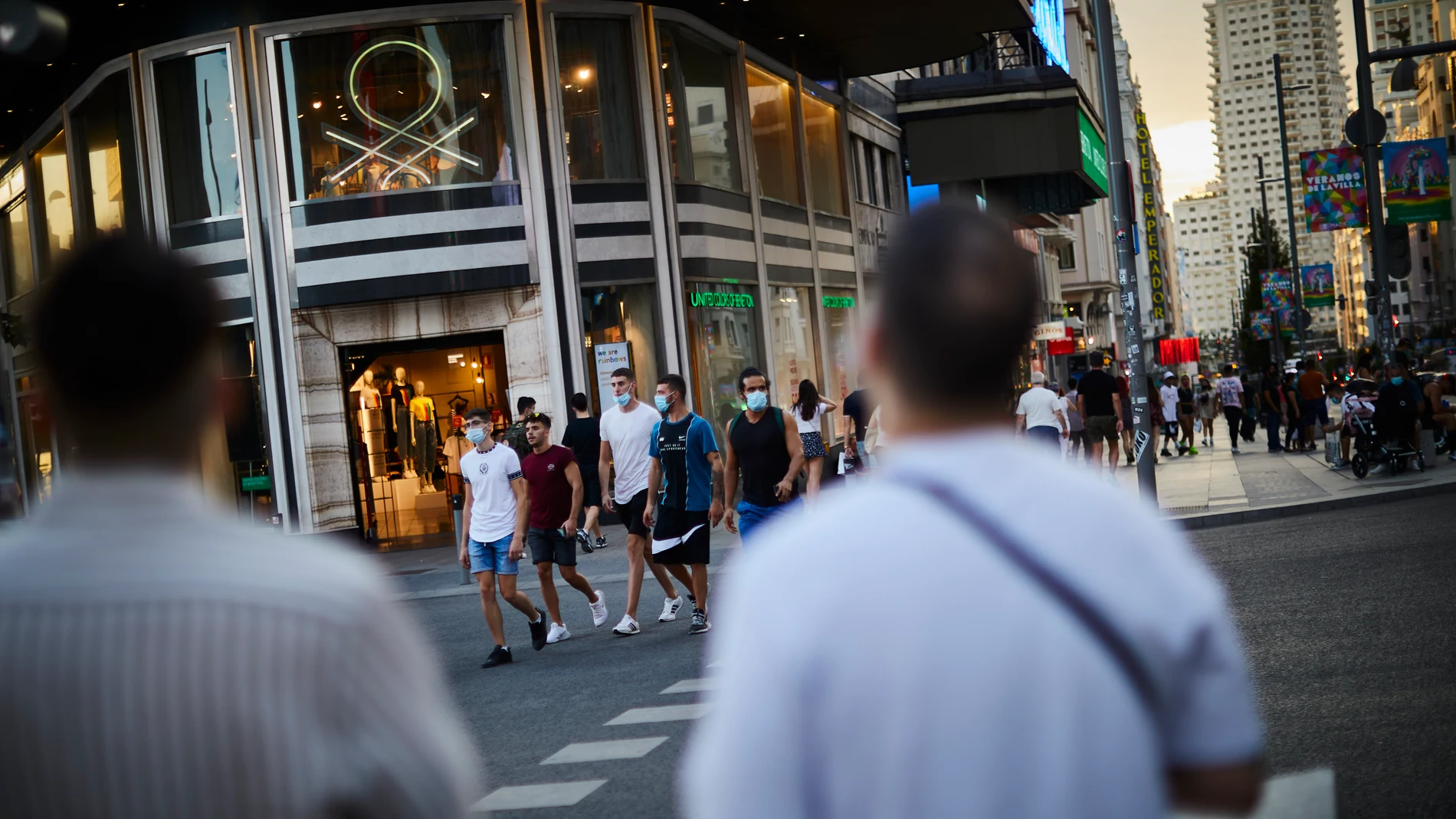 Unos jóvenes caminan por la Gran Vía provistos de mascarillas