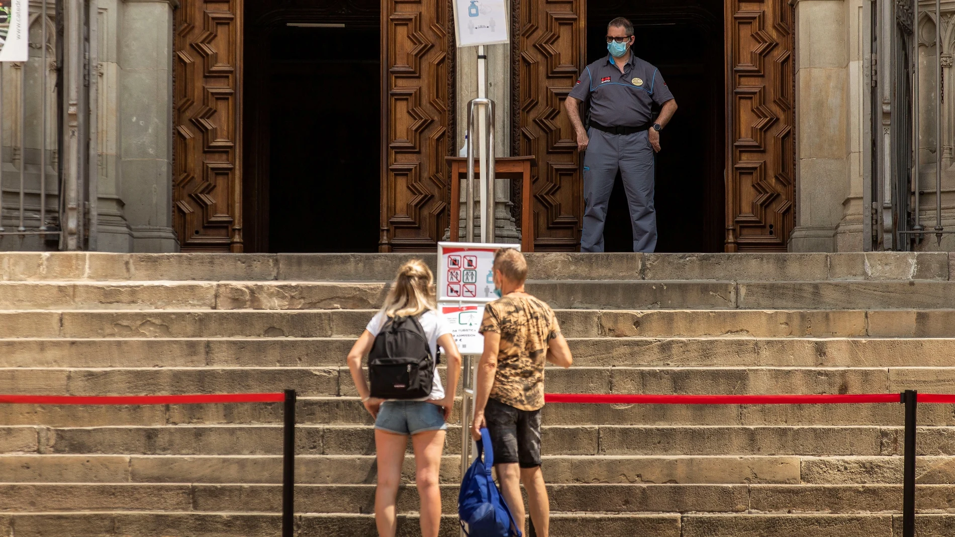 Dos turistas observan este lunes un cartel frente a la entrada de la Catedral de Barcelona