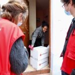 Voluntarios de Cruz Roja entregan dos cajas con ayuda a una familia