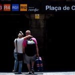 Una pareja de turistas británicos entran en en la estación de Renfe de Plaza Cataluña en Barcelona