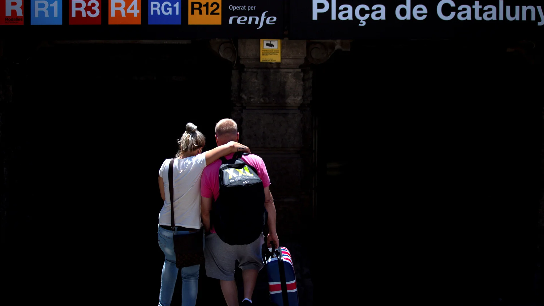 Una pareja de turistas británicos entran en en la estación de Renfe de Plaza Cataluña en Barcelona