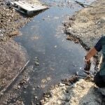 Un agente del Seprona toma muestras del vertido en el río Guadalbullón