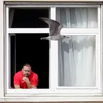 Un miembro de la expedición del Fuenlabrada se asoma a la ventana de la habitación del hotel donde están confinados