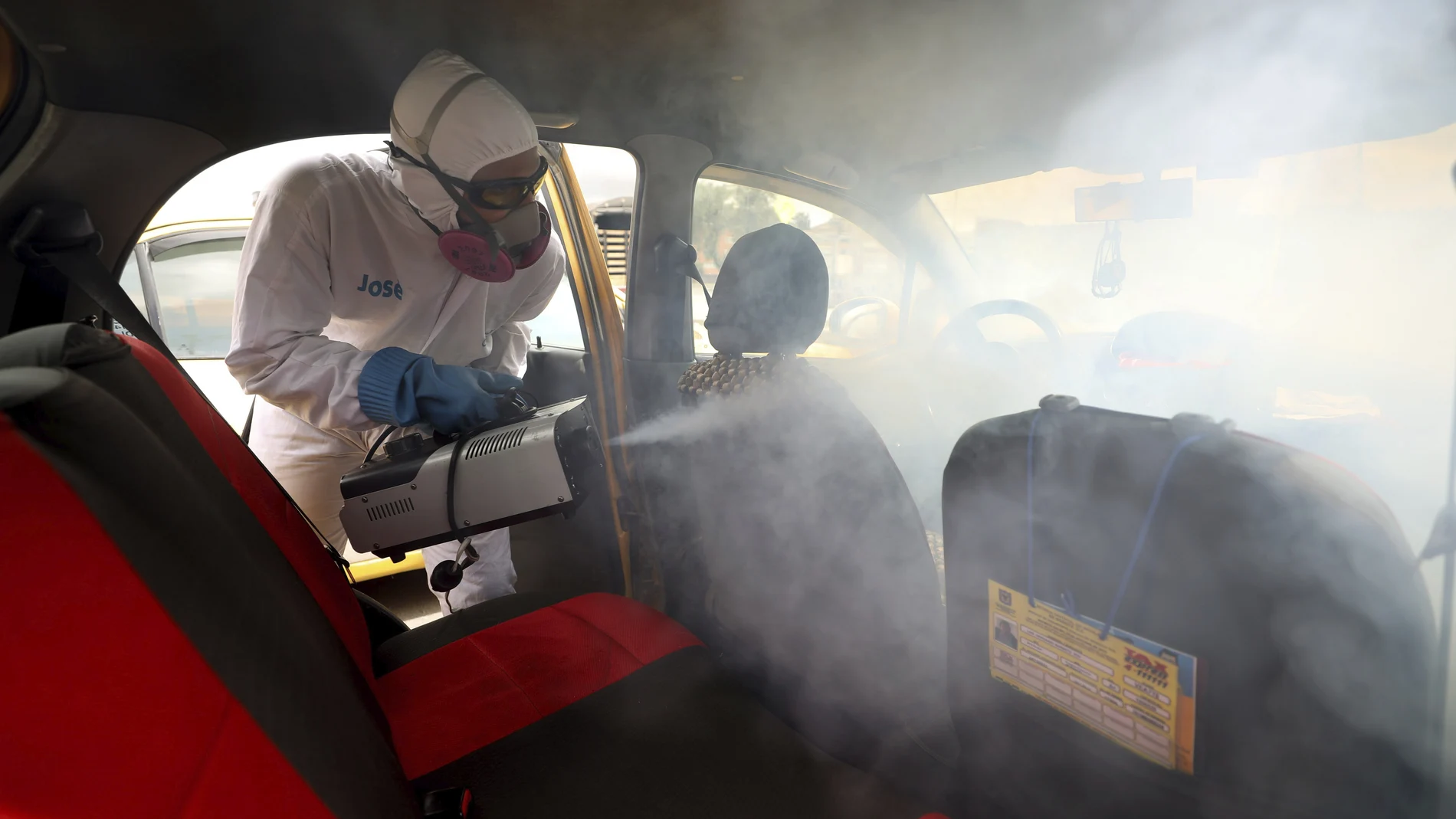 Un trabajador desinfecta un taxi en Bogotá