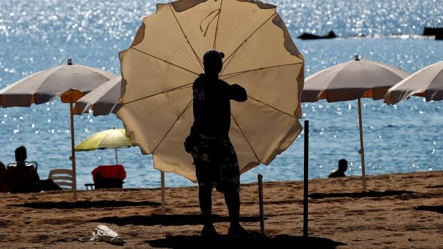 Un trabajador instala las sombrillas y hamacas en la playa de la Barceloneta