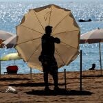 Un trabajador instala las sombrillas y hamacas en la playa de la Barceloneta