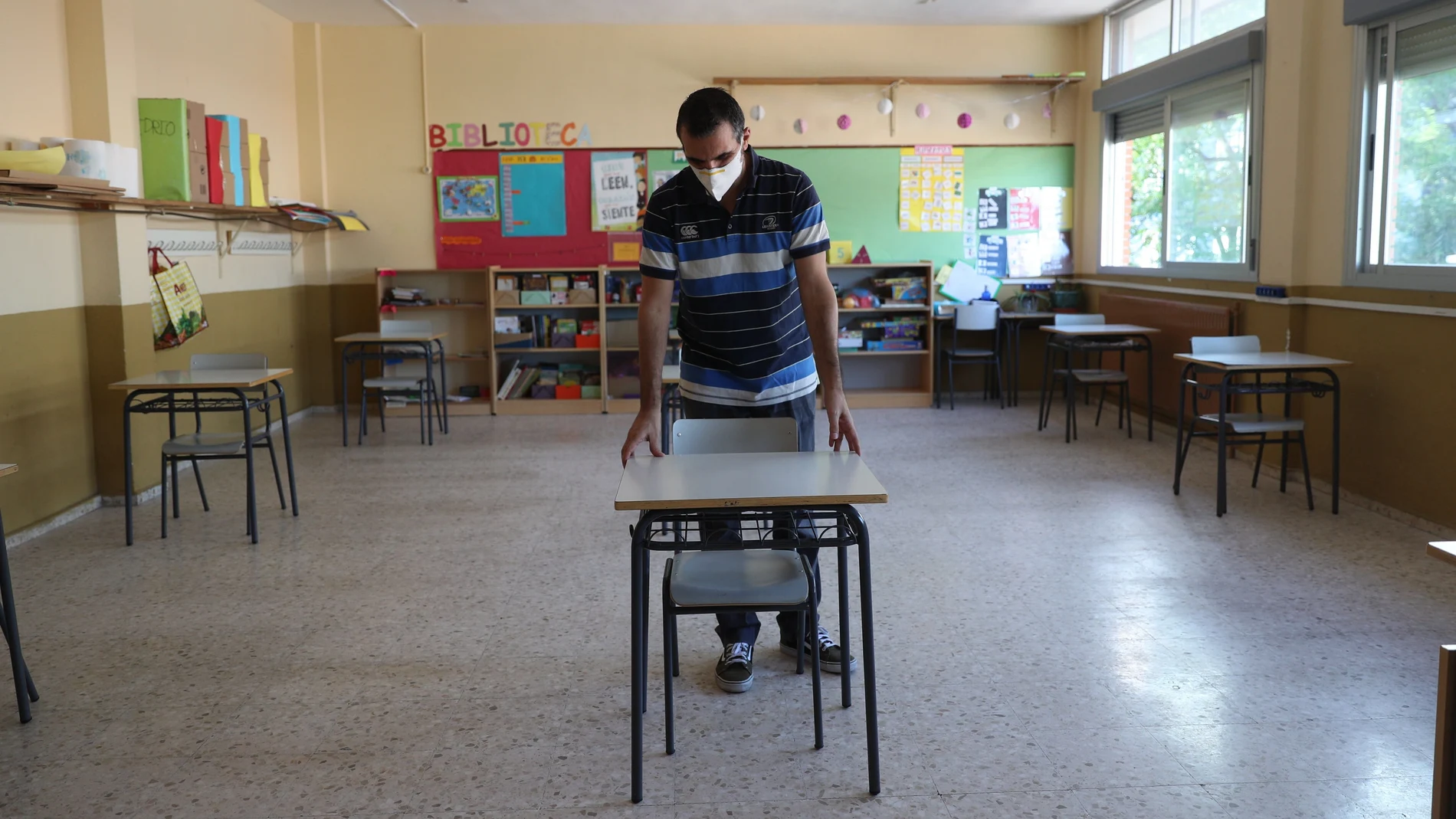 Un profesor coloca las mesas para mantener la distancia de seguridad en el colegio Jaime Vera en Torrejón de Ardoz