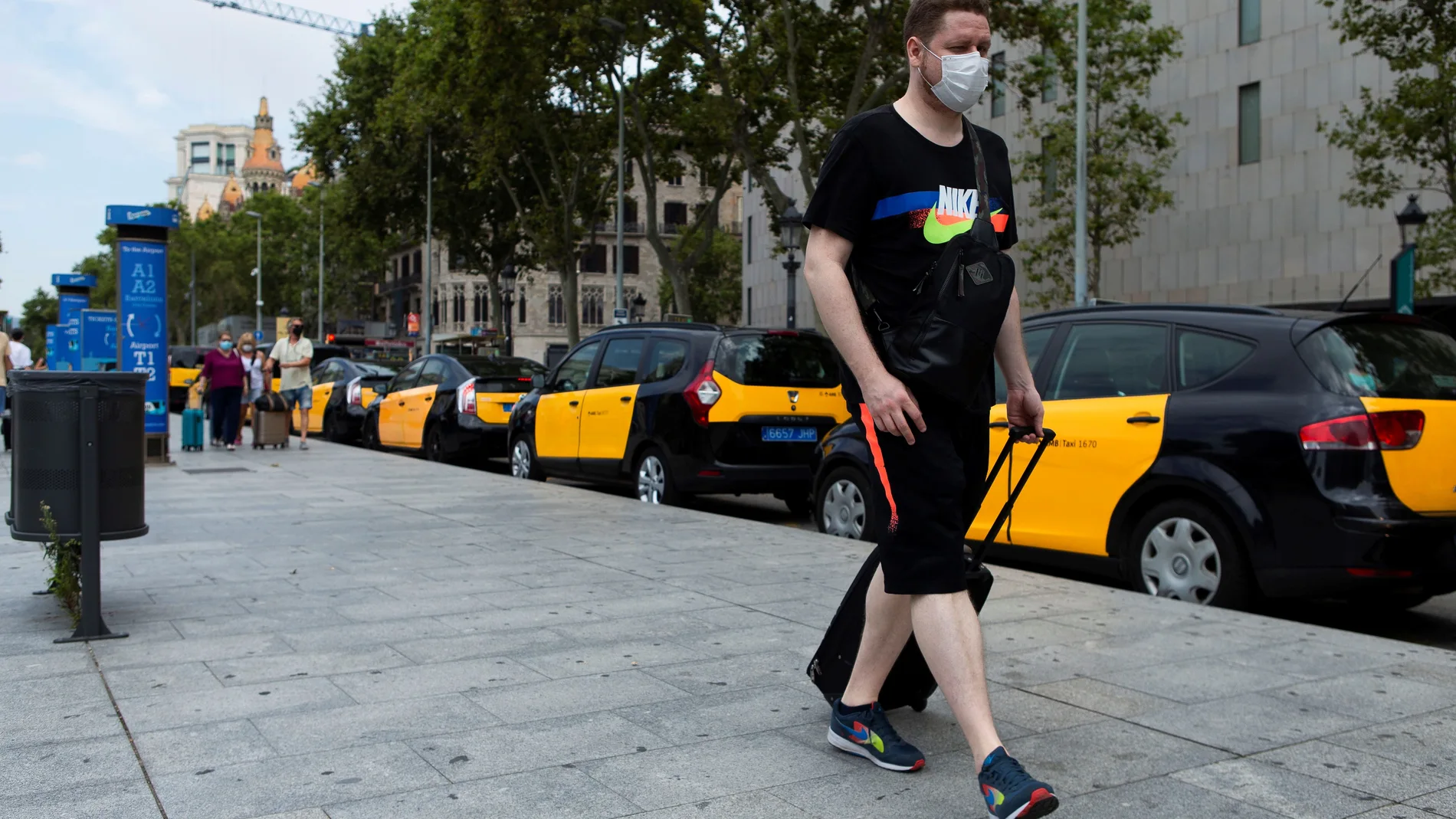 Un turista camina ante una hilera de taxis aparcados en el centro de Barcelona este martes cuando el sector turístico catalán se enfrenta a un nuevo parón