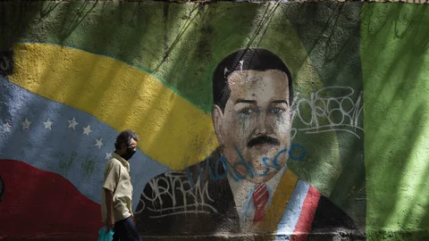 A man wearing a face mask amid the COVID-19 pandemic passes a mural of Venezuelan President Nicolas Maduro in Caracas, Venezuela, Wednesday, July 22, 2020. Analysts say that in recent months the pandemic has helped suck away the opposition’s scanty momentum and bolster Maduro’s already strong hand. (AP Photo/Ariana Cubillos)