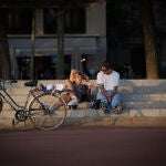 Dos jóvenes descansan junto a una bicicleta en Barcelona