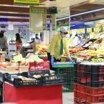 Una trabajadora coloca las frutas y verduras en un supermercado.