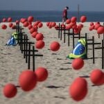GRAF056. RÍO DE JANEIRO (BRASIL), 08/08/2020.- Fotografía de una representación escénica de la ONG Río de Paz por las víctimas del COVID-19 hoy, en la playa de Copacabana en Río de Janeiro (Brasil). Con mil globos rojos en las arenas de la playa y cien de ellos fijados en cien cruces negras se rindió homenaje a los 100 mil brasileños fallecidos por la pandemia de coronavirus y se manifestaron en contra de la forma en que el Gobierno ha gestionado la crisis sanitaria. EFE/Antonio Lacerda