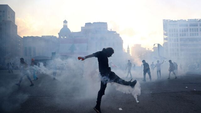 Un manifestantes pega una patada a un bote de gas lacrimógeno en una protesta en Beirut por la explosión del puerto