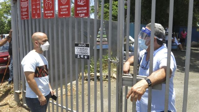 An electoral official, right, tells a voter that the ballots haven't arrived at a voting center in Carolina, Puerto Rico, Sunday, Aug. 9, 2020. Puerto Rico's primaries were marred on Sunday by a lack of ballots in a majority of centers across the U.S. territory, forcing frustrated voters who braved a spike in COVID-19 cases to turn around and go back home. (AP Photo/Danica Coto)