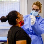 Una trabajadora sanitaria protegida realiza un test a una mujer