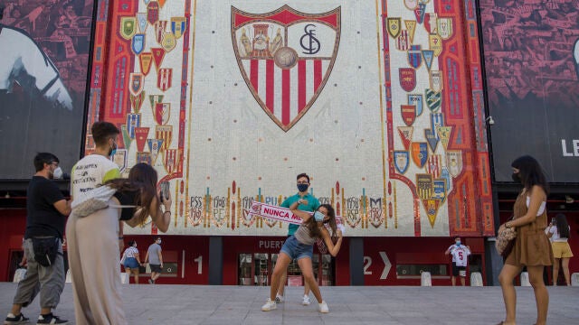 Varias personas se fotografían ante el escudo del Sevilla FC durante las horas previas al partido final de la Europa League Sevilla FC - Inter de Milán, en las inmediaciones del estadio Ramón Sánchez Pizjuán.