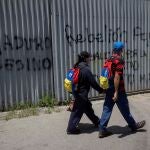 Personas caminan frente a un grafitis con mensaje en rechazo al presidente de Venezuela, Nicolás Maduro, en Caracas
