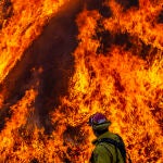 Un bombero pasa junto a una columna de fuego en el valle Moreno (California)
