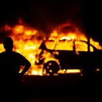 Un manifestante contempla la quema de vehículos durante las protestas en Kenosha