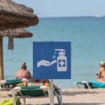 Un cartel en la playa de Palma de Mallorca recuerda la necesidad de usar gel desinfectante para evitar contagios