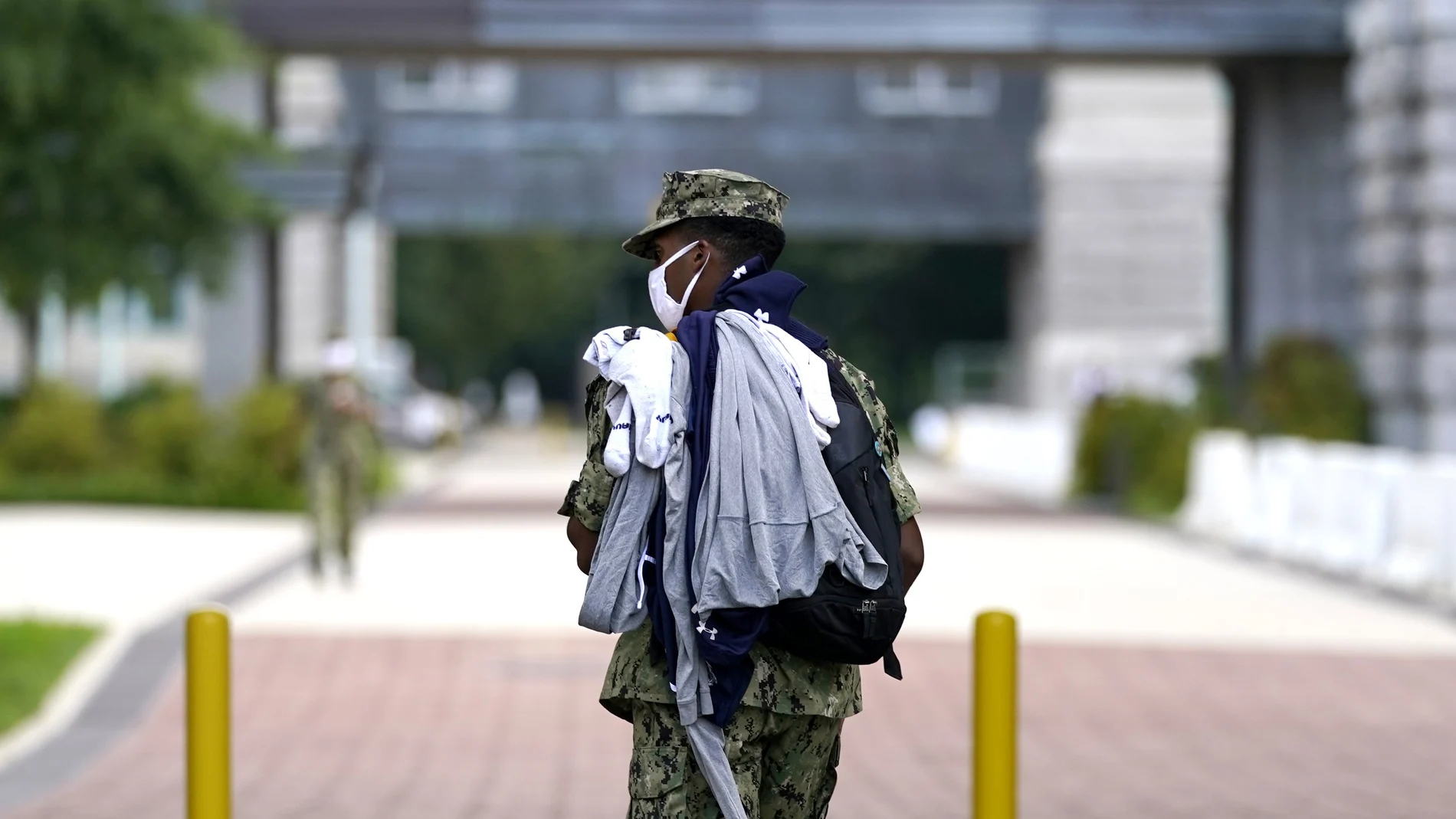 A midshipman wears a face mask to protect against COVID-19 while walking with laundry at the U.S. Naval Academy, Monday, Aug. 24, 2020, in Annapolis, Under the siege of the coronavirus pandemic, classes have begun at the Naval Academy, the Air Force Academy and the U.S. Military Academy at West Point. But unlike at many colleges around the country, most students are on campus and many will attend classes in person. Md. (AP Photo/Julio Cortez)