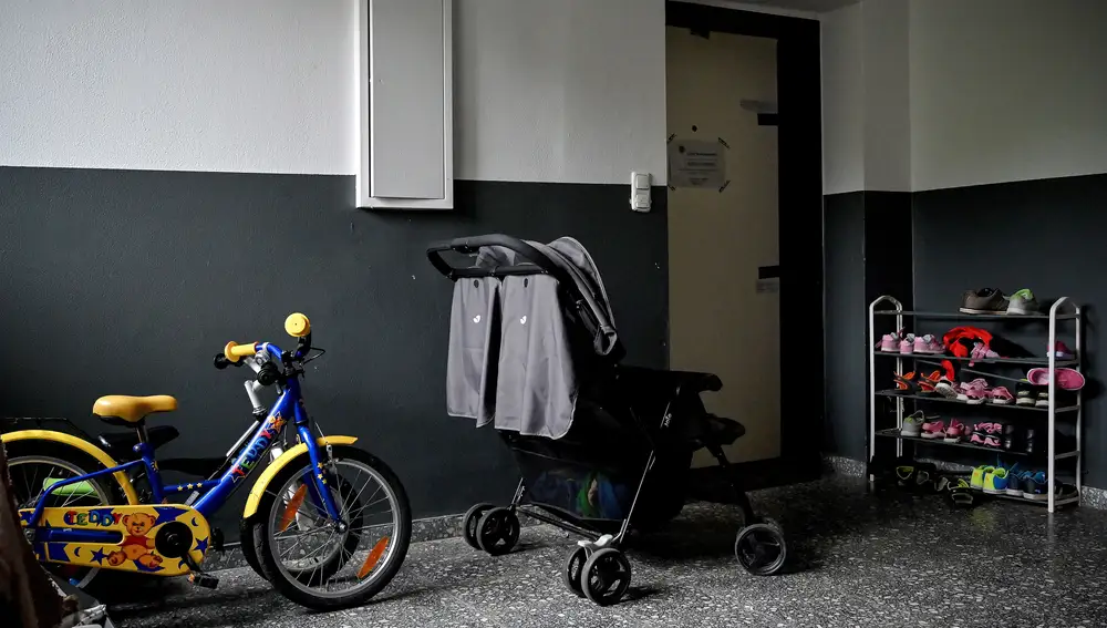 Imagen ampliada de la entrada del apartamento de los horrores. Puede verse el carrito doble, las zapatillas y una bicicleta