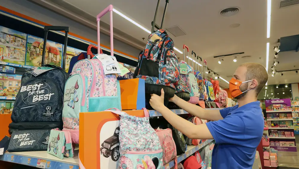 Un dependiente coloca las mochilas en su establecimiento