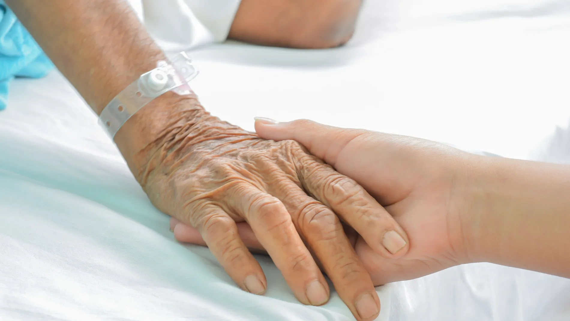 Hospital patient hands to care on bed.