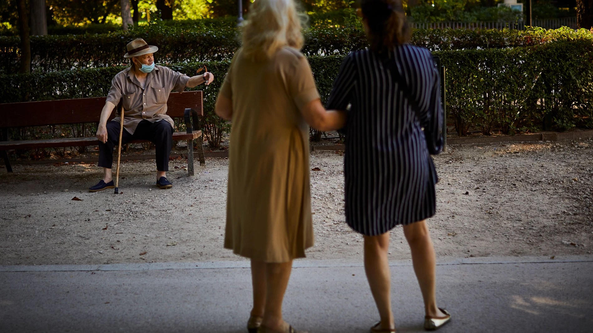 Una persona mayor descansa en un banco del madrileño parque de El Retiro