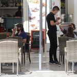 Un camarero atiende a unos clientes en la terraza de un bar